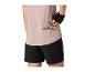 Femme en t-shirt de sport beige et short noir sortant une barre énergétique de sa poche.
