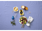 Miel, salade et décorations de Noël sur une table violette.