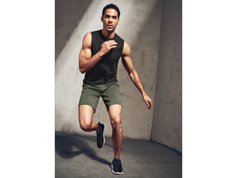 Homme en débardeur noir et short vert faisant un exercice.