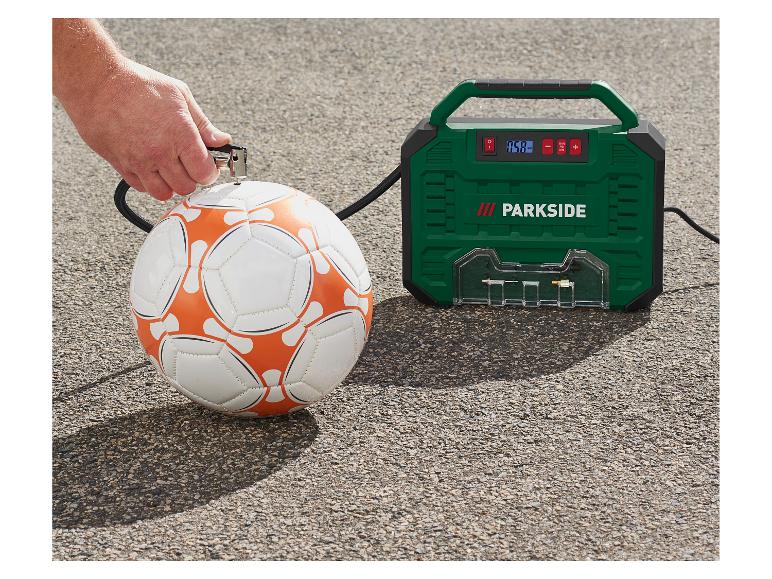 Un homme gonfle un ballon de football avec un compresseur d'air vert.