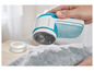 Un rasoir à peluches Philips bleu est utilisé pour enlever les peluches d'un pull gris.