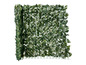Haie artificielle verte avec des feuilles sur une grille.
