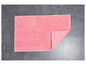 Un tapis de bain rose avec une texture rugueuse, posé sur un carrelage gris.