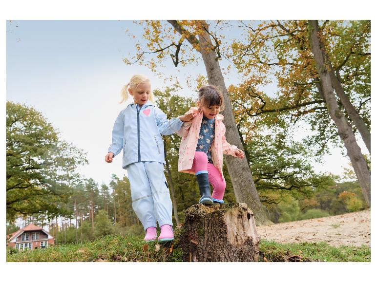 Deux filles en tenue de pluie, incluant vestes et pantalons, jouant dehors.