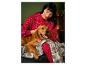 Une femme en pyjama rouge à motif flocons de neige câline son chien.
