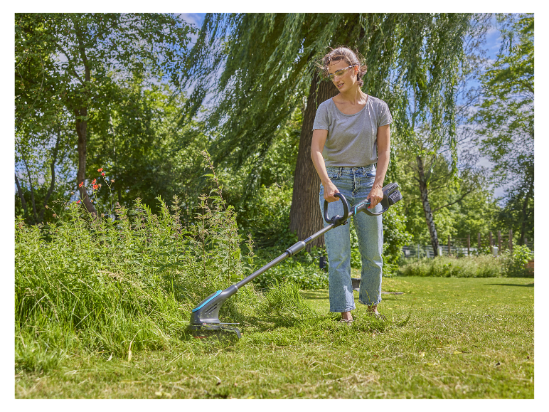 Une femme utilise une débroussailleuse électrique Gardena pour entretenir son jardin.