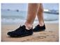 Chaussures noires pour hommes sur le sable, avec la mer en arrière-plan.