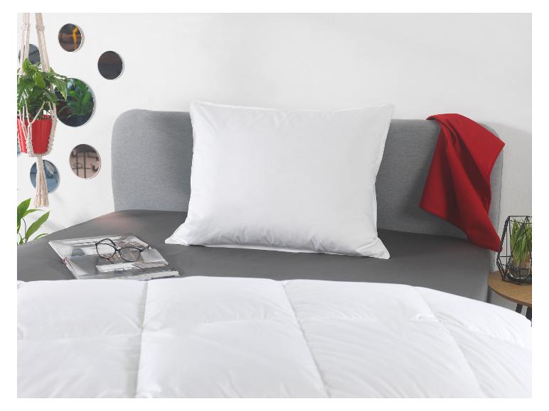 Chambre avec oreiller blanc, couette, linge de lit gris et plaid rouge.