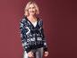 Une femme porte un pull de Noël bleu à motif de renne.