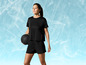 Une femme portant un haut et un short Reebok noirs tient un ballon d'entraînement.