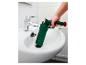 Un homme utilise une ventouse de vidange verte pour déboucher un lavabo de salle de bain.