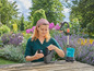 Une femme utilise une pompe et un filtre Gardena pour arroser son jardin.