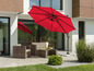 Un parasol rouge au-dessus d'une terrasse avec des chaises en osier.