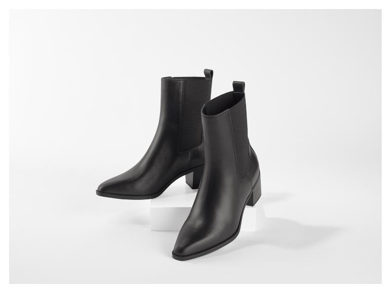 Une paire de bottines en cuir noir à talons blocs sur fond blanc.