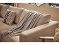 Canapé beige avec coussin décoratif rayé et plaid gris.