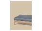 Matelas gris sur un cadre de lit en bois sur fond beige.