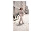Femme en costume clair marchant dans une rue pavée, souriante.