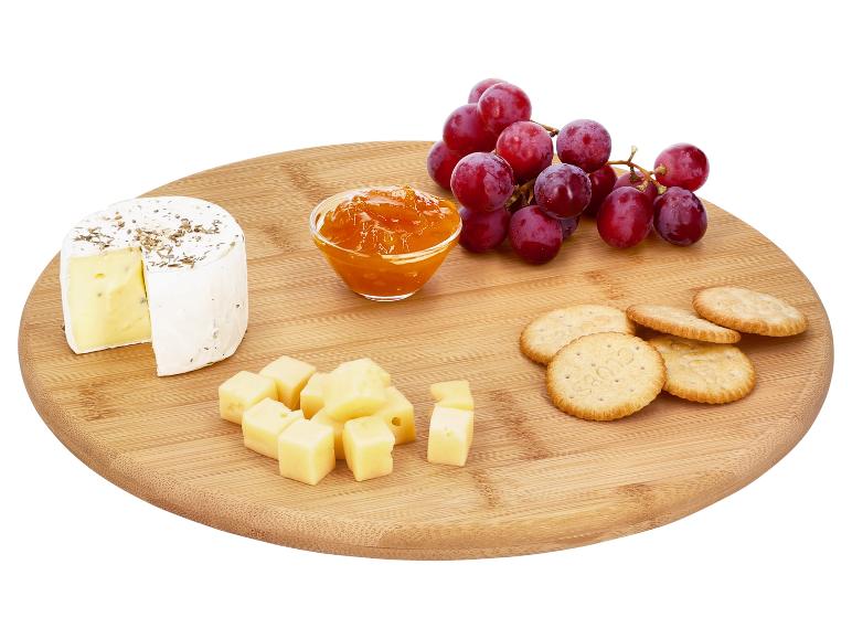 Planche de fromages avec brie, fromage en dés, crackers, confiture et raisins rouges.