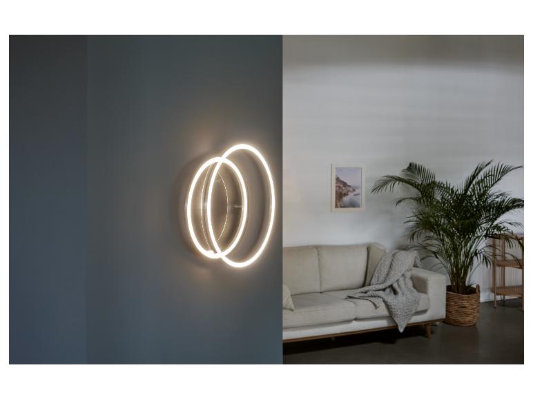 Un luminaire mural moderne avec deux anneaux dans un salon.