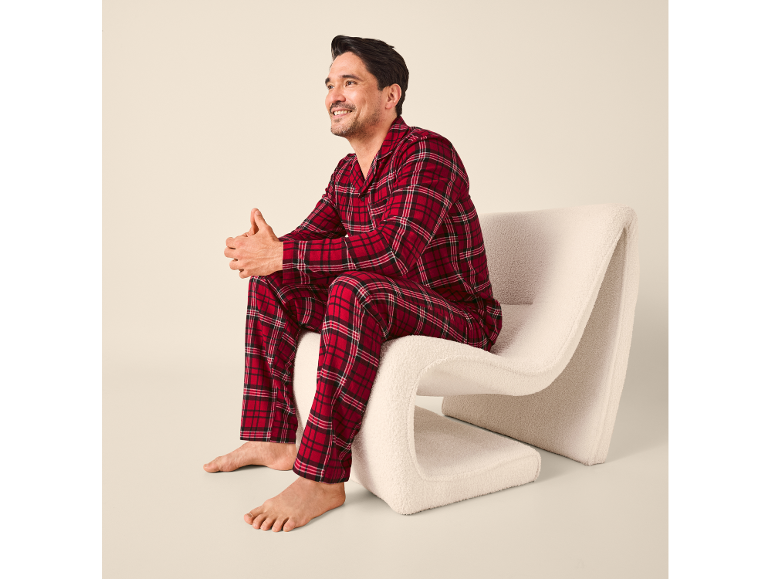 Homme en pyjama à carreaux rouges assis sur une chaise blanche moderne.