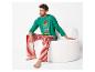 Homme assis sur une chaise blanche en pyjama de Noël vert avec l'inscription 'let's take an Elfie' et un pantalon rayé rouge et blanc.