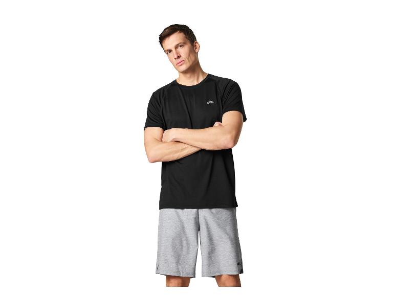 Homme en t-shirt de sport noir et short de sport gris, bras croisés