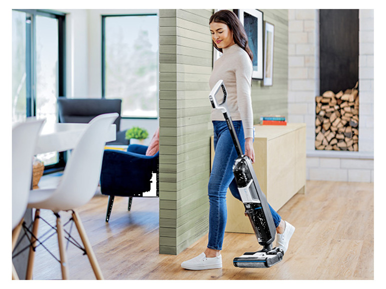 Une femme nettoie un sol en bois avec une nettoyeuse vapeur Kärcher.