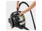 Aspirateur eau et poussière avec des mains fixant le tuyau à l'appareil.