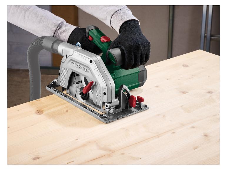 Une scie circulaire sans fil coupe une planche de bois, avec un tuyau d'aspiration des poussières.
