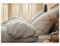 Draps et oreillers en lin beige clair dans une chambre à coucher chaleureuse.