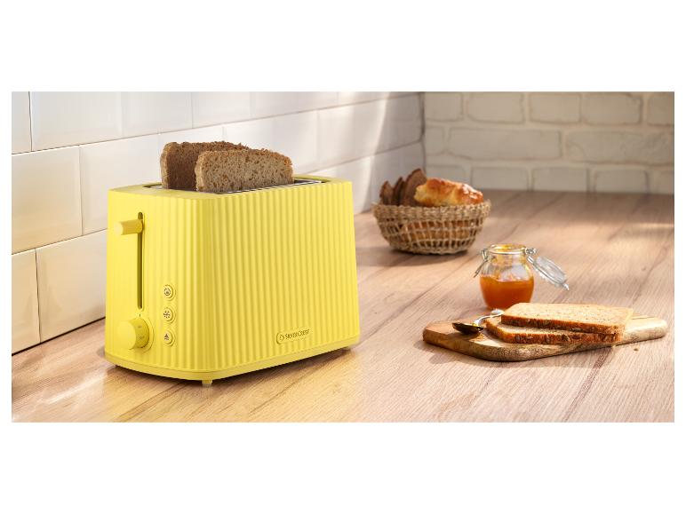 Grille-pain jaune SilverCrest avec toasts, confiture et panier de pain dans la cuisine.
