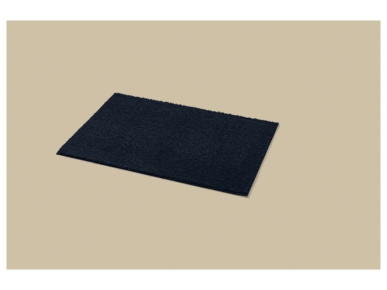 Un tapis de bain bleu foncé sur un fond beige