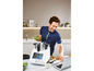 Un homme cuisine avec un Thermomix et un ordinateur portable dans la cuisine.