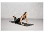 Une femme faisant des exercices sur un tapis de yoga noir Adidas.