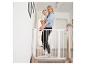Mère avec bébé ouvrant une barrière de sécurité pour escalier.