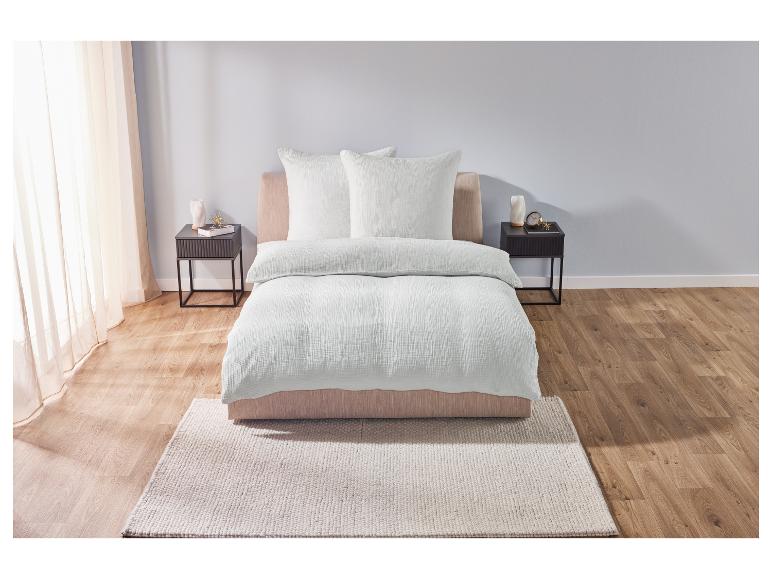 Une housse de couette en coton blanc sur un lit avec deux oreillers.