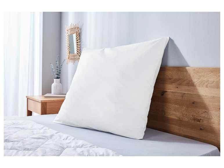 Une couette et un oreiller blancs sur un lit avec une tête de lit en bois.