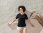 Une femme portant un t-shirt noir et un short beige.