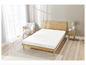 Un surmatelas blanc avec un motif ondulé sur un cadre de lit en bois dans une chambre à coucher.