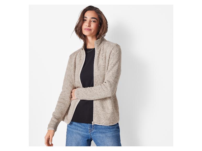 Une femme en veste polaire beige et jean.