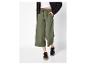 Pantalon culotte vert avec cordon, top blanc et veste noire.
