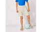 Un garçon porte un short beige, des sandales et un t-shirt bleu pendant qu'il joue au volley-ball.