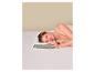 Femme dormant sur le côté sur un oreiller ergonomique dans un lit aux draps blancs.