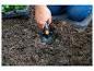 Personne plantant dans le jardin avec une petite pelle et un coussin de jardinage.