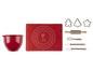 Un bol rouge, un tapis de cuisson en silicone rouge avec un motif de renne et des accessoires de pâtisserie.