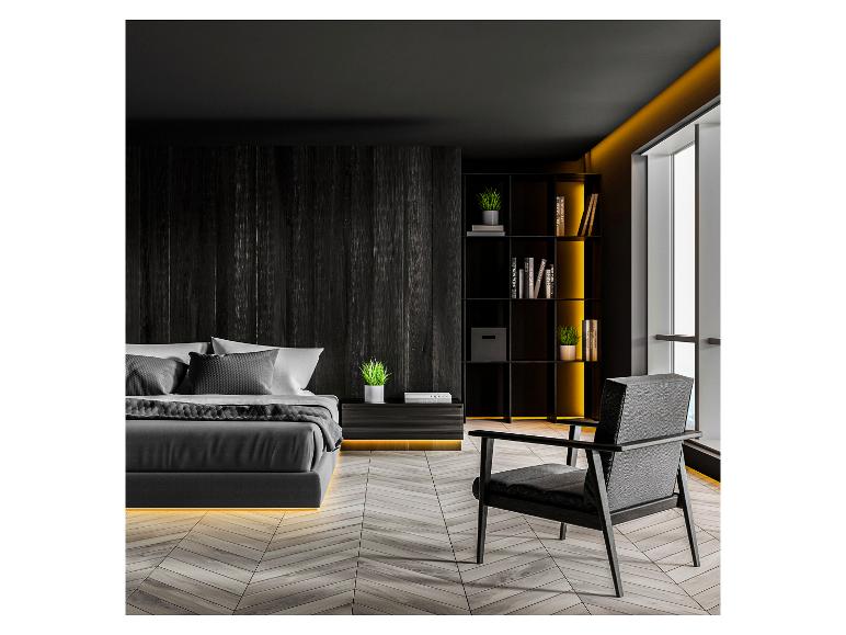 Chambre moderne sombre avec lit, fauteuil et bibliothèque avec éclairage décoratif.