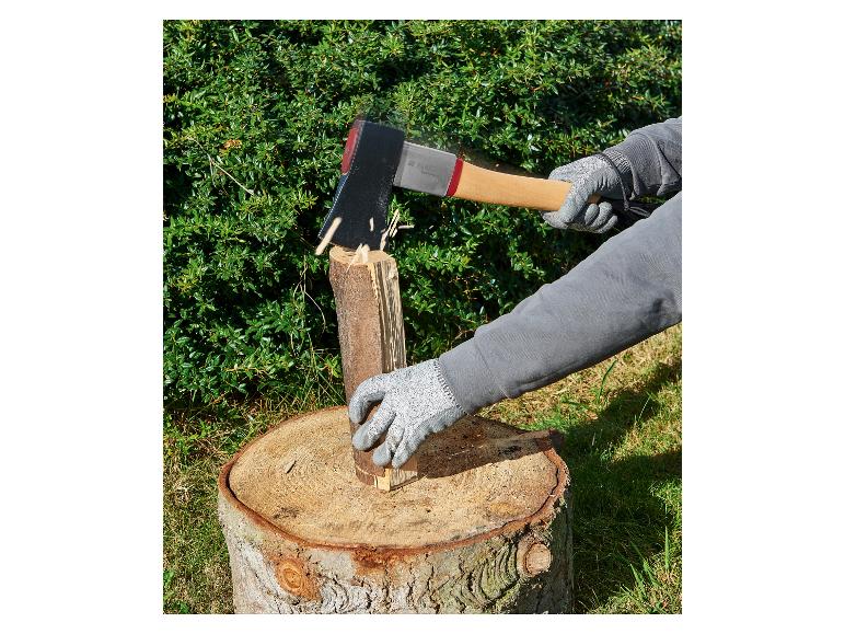 Une personne utilisant une hache Fiskars pour fendre du bois sur une souche d'arbre.