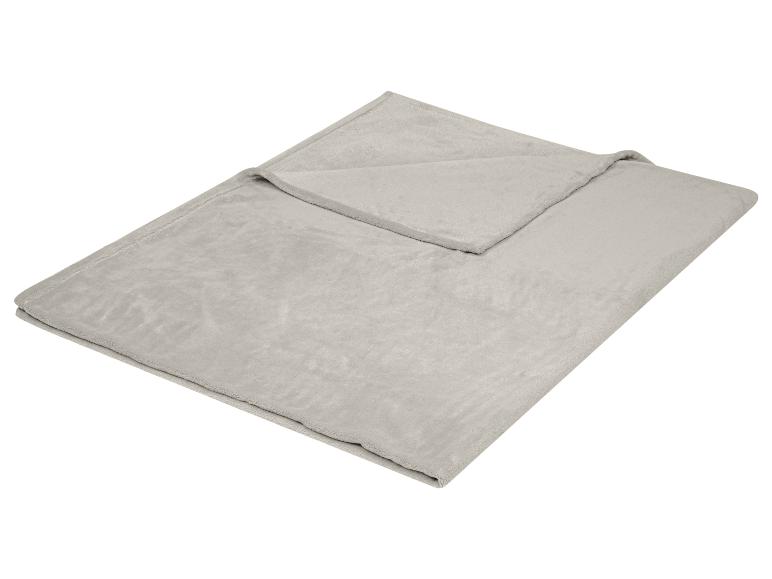 Plaid polaire gris et doux plié sur fond blanc.