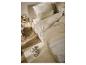 Chambre à coucher avec un lit au linge de lit beige, une table de chevet et un tapis avec des chaussons.