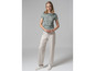 Une femme portant un t-shirt bleu clair à motif et un pantalon beige.